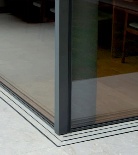 Minimal corner stile meeting a flush multi-track threshold